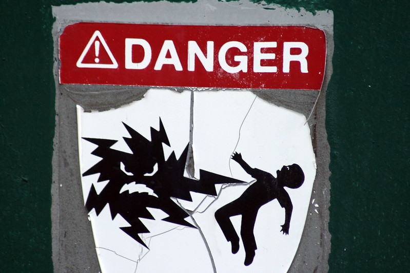 A danger sign with a bolt of energy striking a person